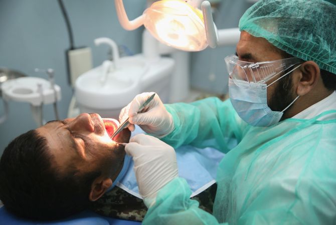 A dentist conducts an oral examination of one his patients.