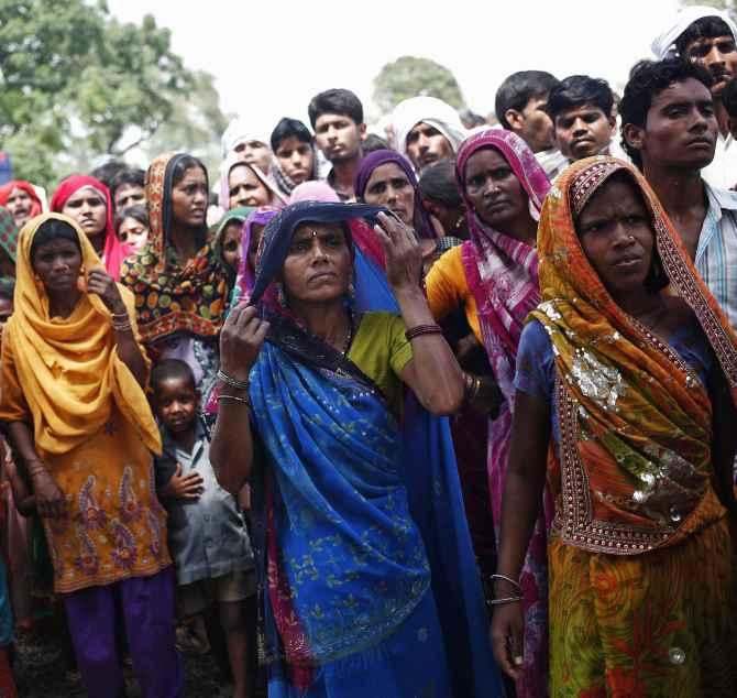 Onlookers stand at the site where two teenage girls were raped and hanged from a tree at Budaun district in UP