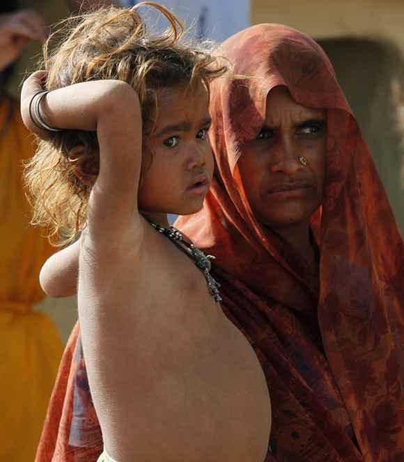 A malnourished child stands next to her mother in UP's Lalitpur district