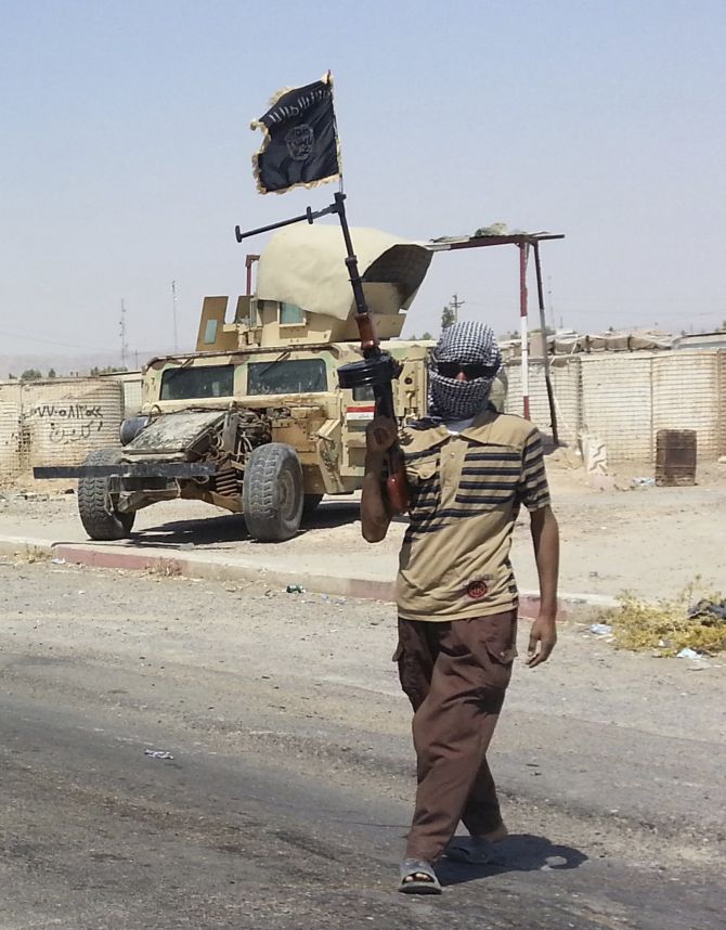 A fighter of the ISIS stands guard at checkpoint near the city of Baij, Iraq