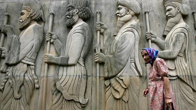 An elderly Parsi woman walks by a fire temple in Mumbai.