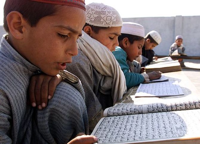 Boys seated in a row study at a madrasa in India.