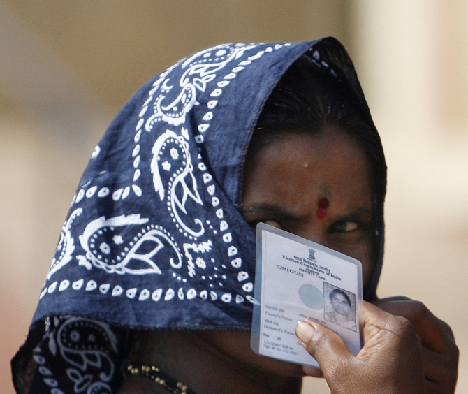 A woman holds her voting card near Mumbai
