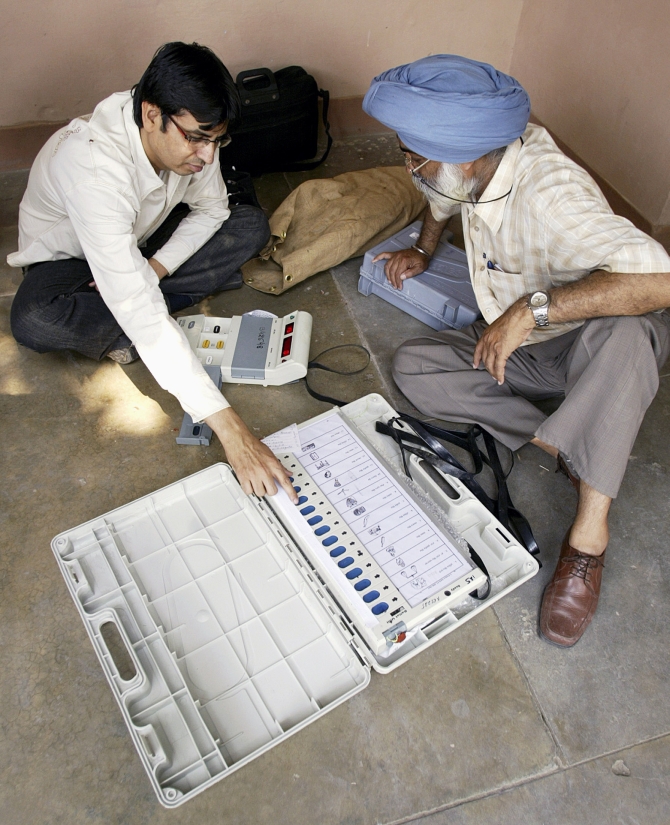 Polling officers check an EVM at a distribution centre in Amritsar