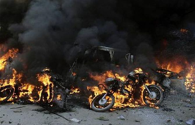 Damaged vehicles burn after a bomb blast in Guwahati in this October 30, 2008 file photo