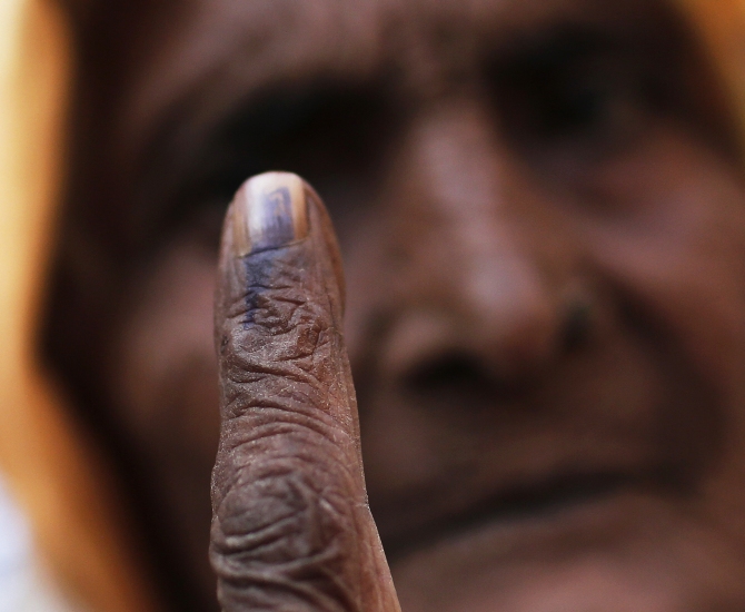 A woman shows her ink-marked finger after casting her vote at a polling station during the state assembly election in this photograph