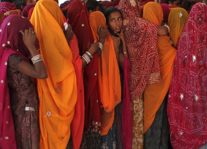 Women line up in a queue outside a polling booth to cast their vote during the state assembly election in Birchiwayas village in Ajmer.