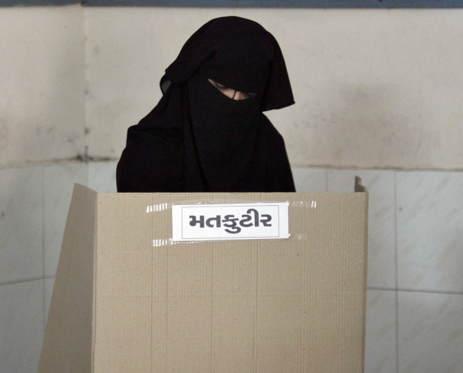 A veiled Muslim woman casts her ballot inside a polling booth during the second phase of state elections in Ahmedabad in this picture taken on December 17, 2012.