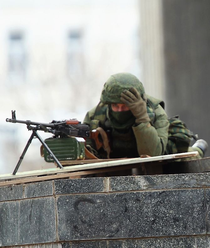 Soldiers without identifying insignia man machine guns outside the Crimean parliament building in Simferopol, Ukraine.