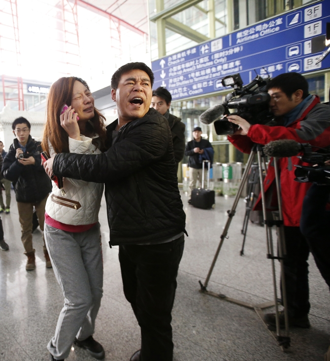 A relative of a passenger onboard Malaysia Airlines flight MH370 cries as she talks on her mobile phone