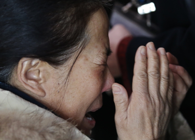 A relative of a passenger onboard Malaysia Airlines flight MH370 cries, surrounded by journalists, at the Beijing Capital International Airport in Beijing