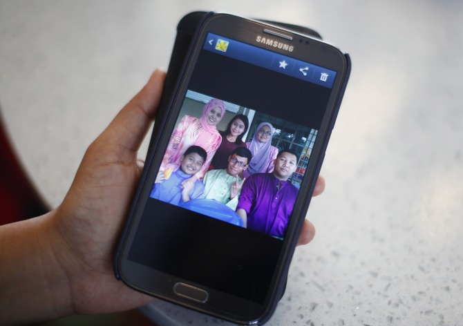 Arni Marlina, 36, a family member of a passenger onboard the missing Malaysia Airlines flight MH370, shows a family picture on her mobile phone, at a hotel in Putrajaya.