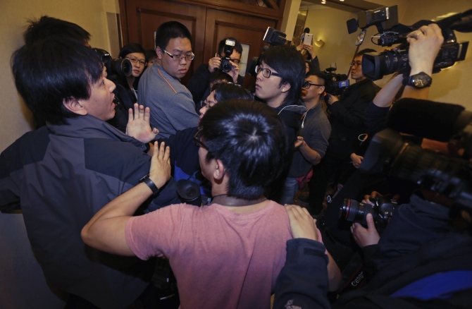 A journalist (left) scuffles with another (centre, with glasses) as they wait for relatives of passengers of Malaysia Airlines flight MH370 at a hotel in Beijing.