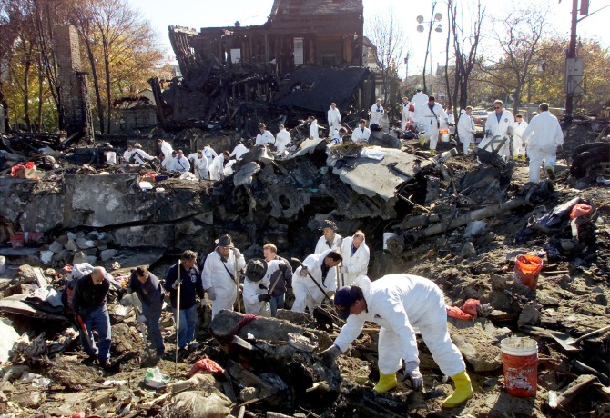 New York City firefighters in protective gear search the pit at the corner of Beach 131st street and Newport Street in the Rockaway Beach section of Queens, New York for human remains and evidence from the crash of American Airlines flight 587.