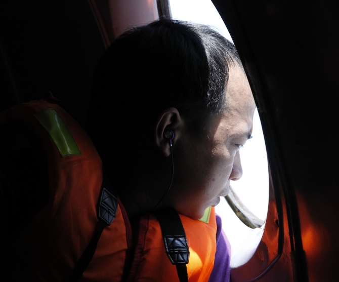 A man looks out a window during a search and rescue mission onboard an aircraft belong to the Vietnamese airforce off Vietnam's Tho Chu island