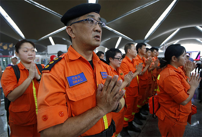 Rescue workers pray for the passengers of Malaysian Airlines flight MH370