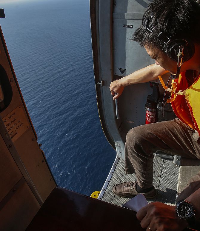 An officer looks out of a helicopter during a mission to find the Malaysia Airlines flight MH370 that disappeared from radar screens in the early hours of Saturday, near Tho Chu island