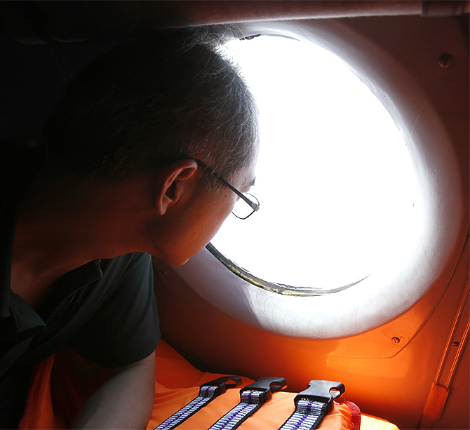 A Chinese journalist looks out from the window of a Vietnamese airforce AN-26 during a mission to find the missing Malaysia Airlines flight