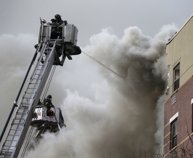 Firefighters try to extinguish a fire at the site of a building collapse in Harlem, New York