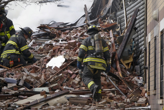 Firefighters go through debris and rubble at the site of a building collapse and fire in Harlem, New York
