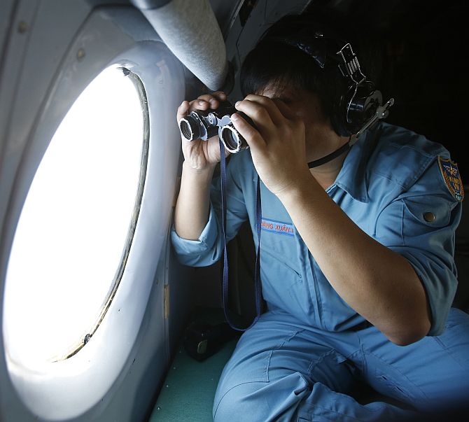 Military officer Dang Xuan Hung looks out a window of a Vietnam Air Force aircraft AN-26 during a mission to find the missing Malaysia Airlines flight MH370