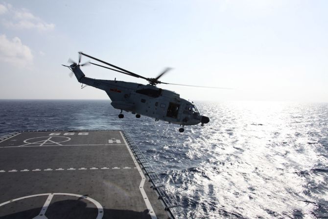 A Chinese helicopter takes off from a warship to search the waters suspected to be the site of the missing flight MH370 