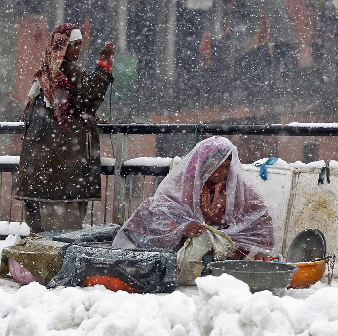 A Kashmiri fisherwoman arranges containers with fish as she waits for customers during heavy snowfall in Srinagar