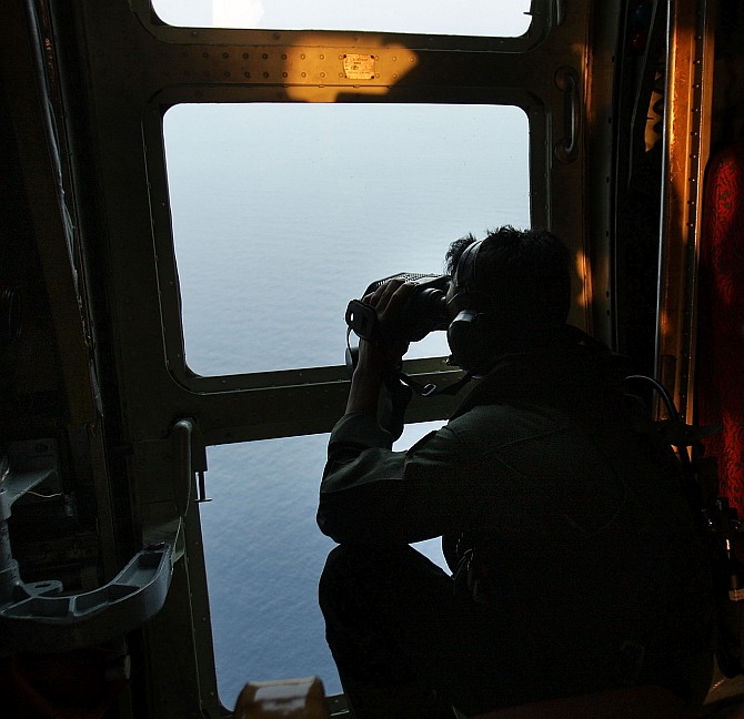 Sgt Zulhelmi Hassan of the Malaysian Air Forces searches the water for signs of debris from the Malaysian airliner during a search and rescue mission flight