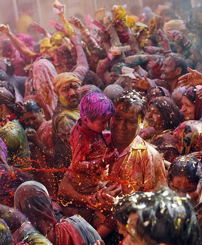 Devotees react as priests (unseen) throw coloured water on them during Holi celebrations at the Bankey Bihari temple in Vrindavan, in Uttar Pradesh