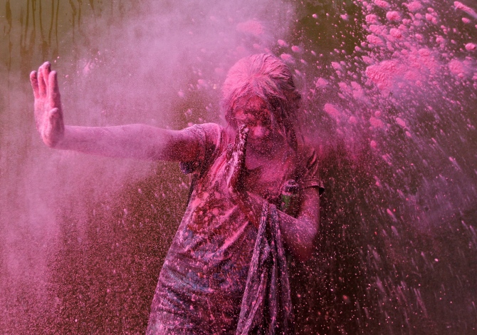 A girl smeared with colours reacts as another girl throws coloured powder at her during Holi celebrations in Chennai.