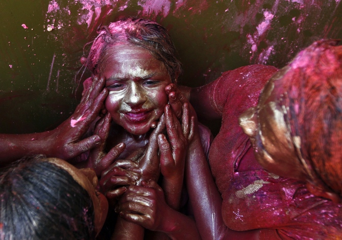 A girl reacts as other girls apply coloured paint on her face during Holi celebrations in  Chennai.
