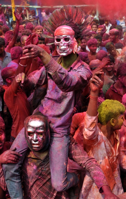 People painted with bright colors dance during Holi in Fancy Bazar, the main commercial centre in Guwahati, on Monday.
