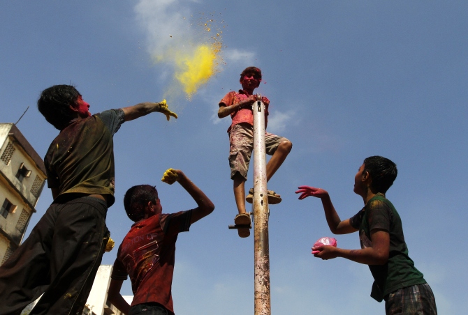 Boys throw coloured powder at another boy standing on a pole as they take part in Holi celebrations in Chennai.