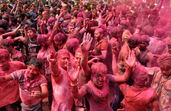 People painted with bright colors dance during the festival of Holi in Fancy Bazar, the main commercial centre in Guwahati, on Monday.