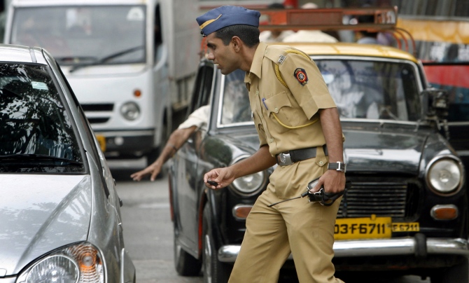 A policeman controls traffic on a busy road in Mumbai