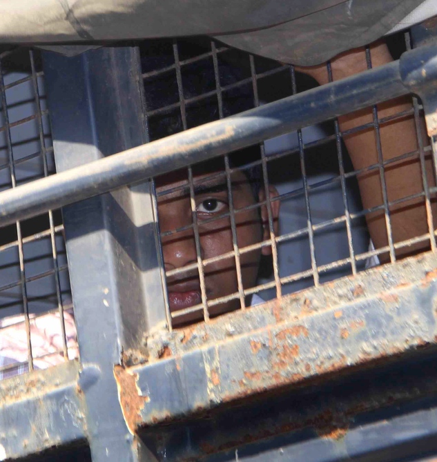 One of the accused is seen in the police van while being brought to the sessions court