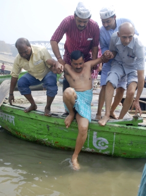 Arvind Kejriwal, helped by supporters, prepares to take a dip in the waters of the Ganga in Varanasi.