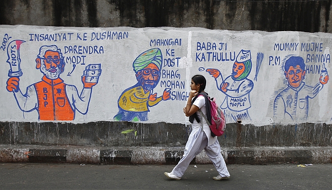 A school girl walks past a wall with graffiti depicting Indian politics ahead of the general election.