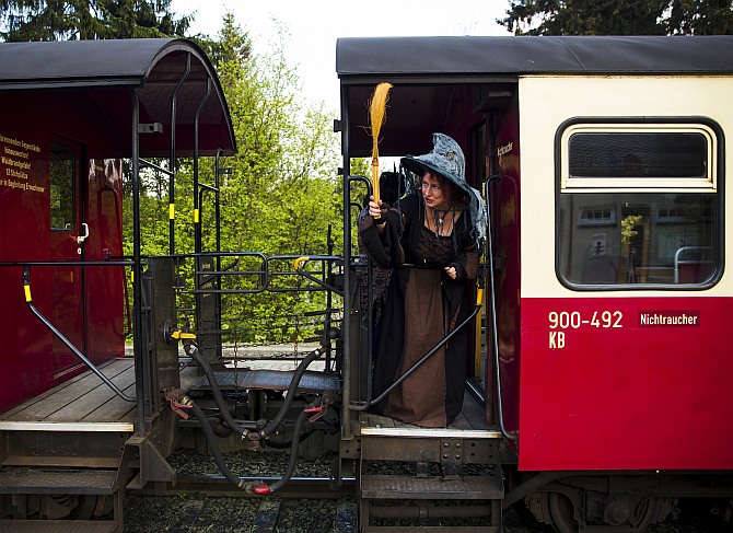 A woman holds a broom as she travels on the HSB light railway through the Harz mountains to celebrate the Walpurgisnacht pagan festival