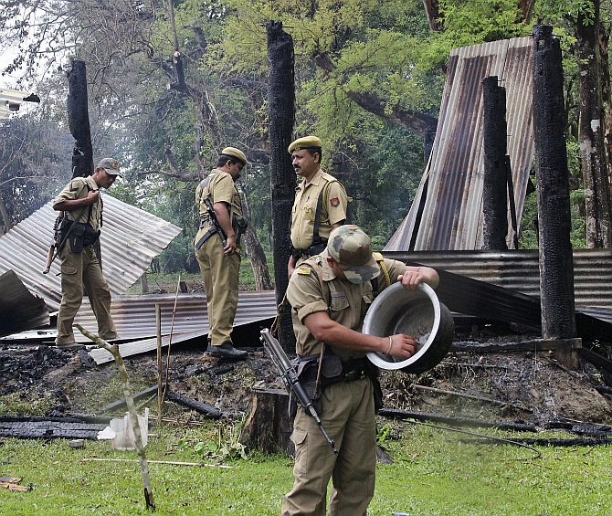 Security personnel inspect the debris of the houses that were burnt during attacks at Baksa district of Assam