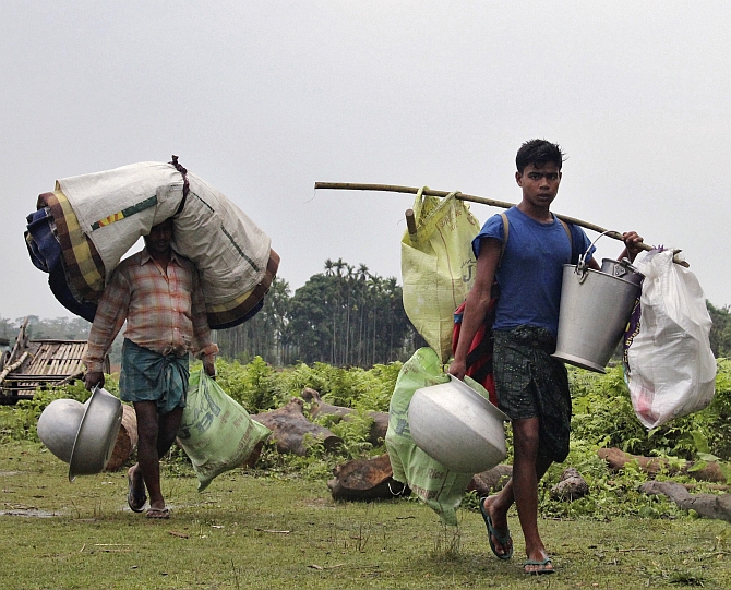 Villagers carry their belongings as they leave their locality after attacks at Baksa district