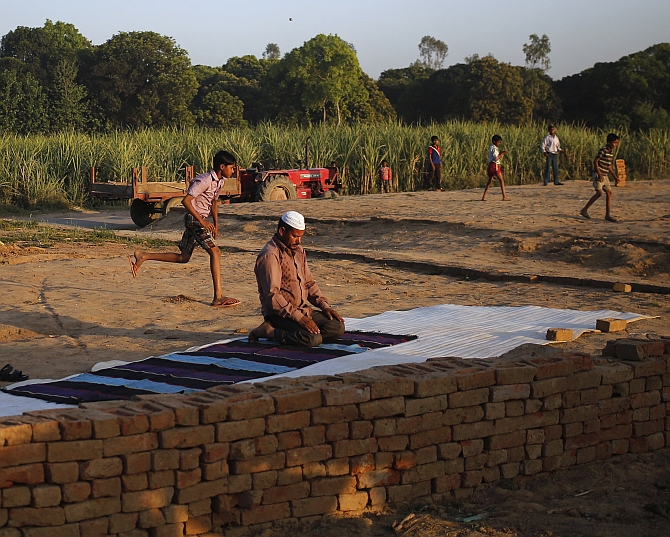 A displaced Muslim man offers prayers next to a relief camp in the village of Kutba at Muzaffarnagar