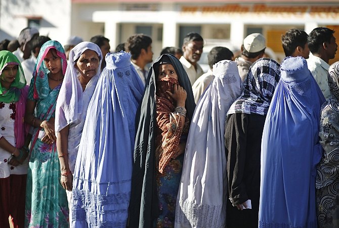 Voters queue at a polling station to cast their votes in Shabazpur Dor village, in Amroha district in UP