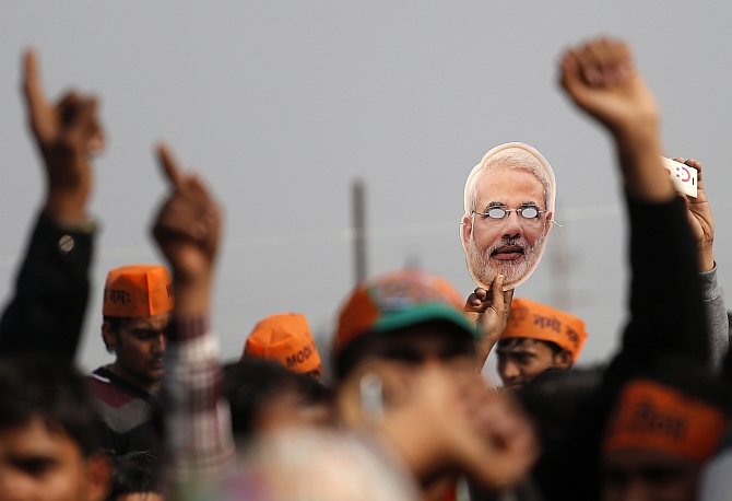 A supporter of Modi holds out a mask during a rally in Meerut