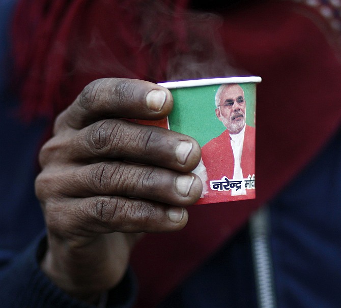 A man with a cup carrying a portrait of Narendra Modi.