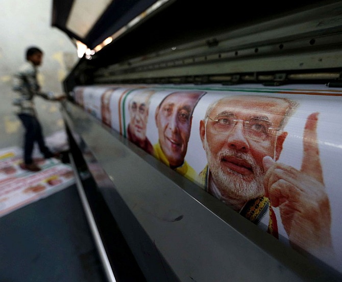 A worker prints banners of Narendra Modi and other BJP leaders.