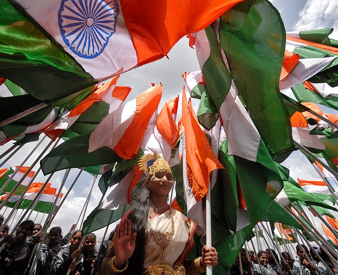 A woman dressed as Mother India poses with national flags