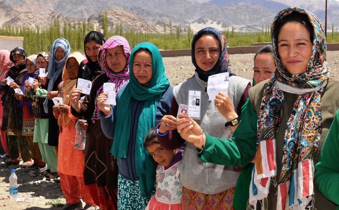 Ladakhi women show their voter cards as they wait in line outside a polling booth