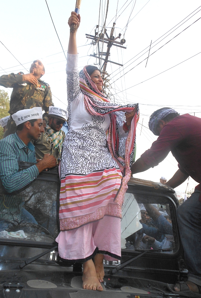 AAP's Shazia Ilmi waves the broom, the party symbol, as she stands atop the jeep