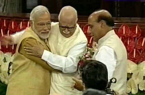 An emotional L K Advani hugs Narendra Modi in Parliament as Rajnath Singh looks on 